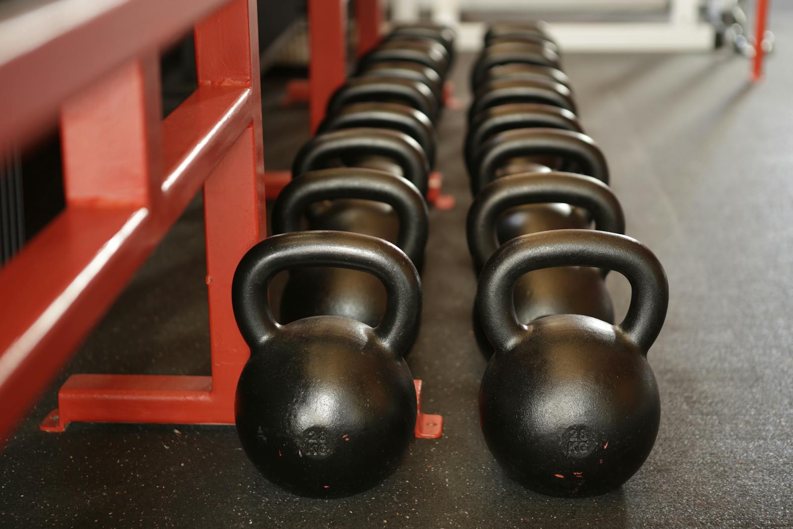 Black kettlebells lined up in a gym, ready for fitness training.